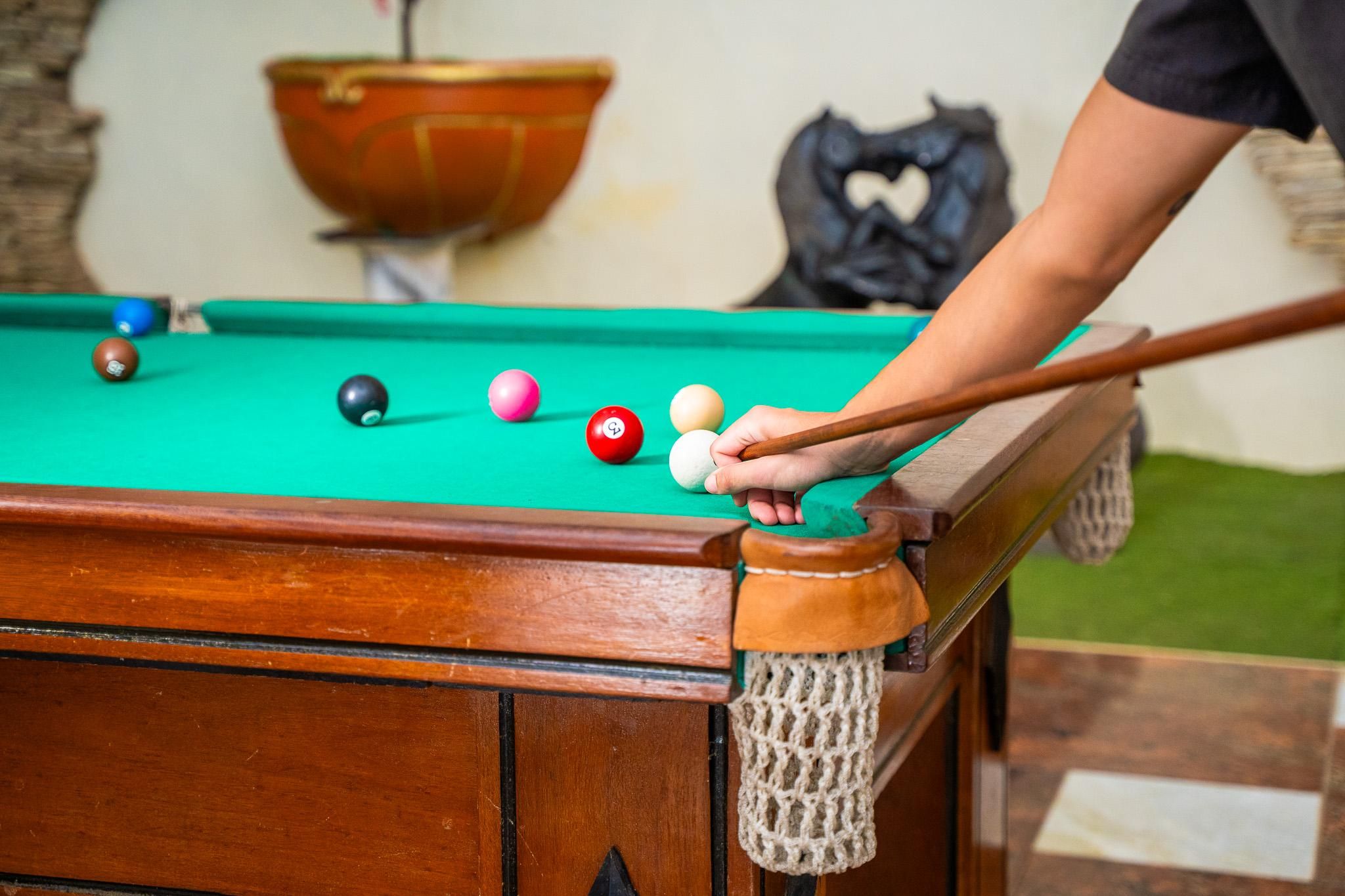 A pool table with balls and a cue stick.