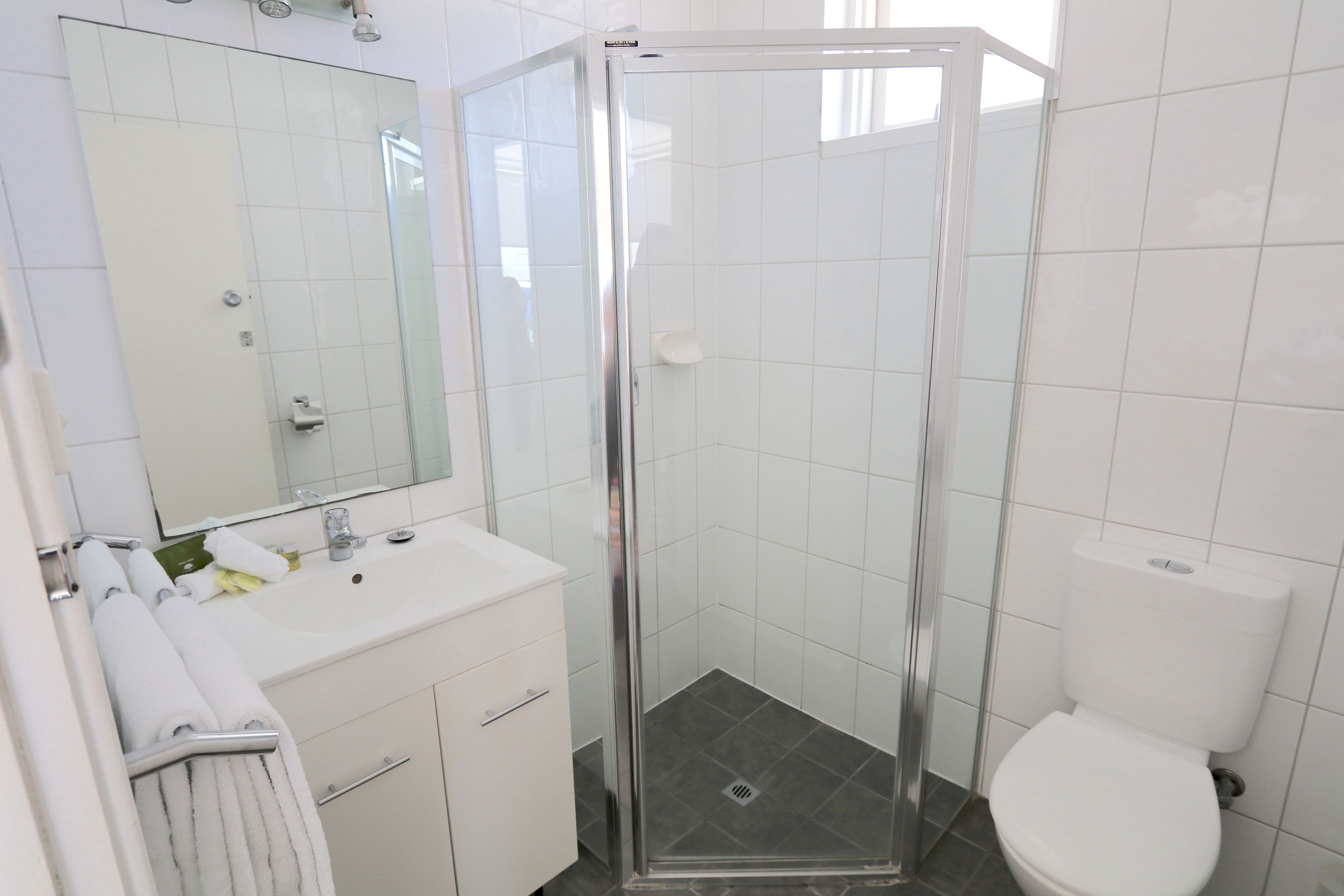 Ein modernes Badezimmer mit einer einteiligen Duschkabine, einem weißen Waschbecken und einer Toilette.