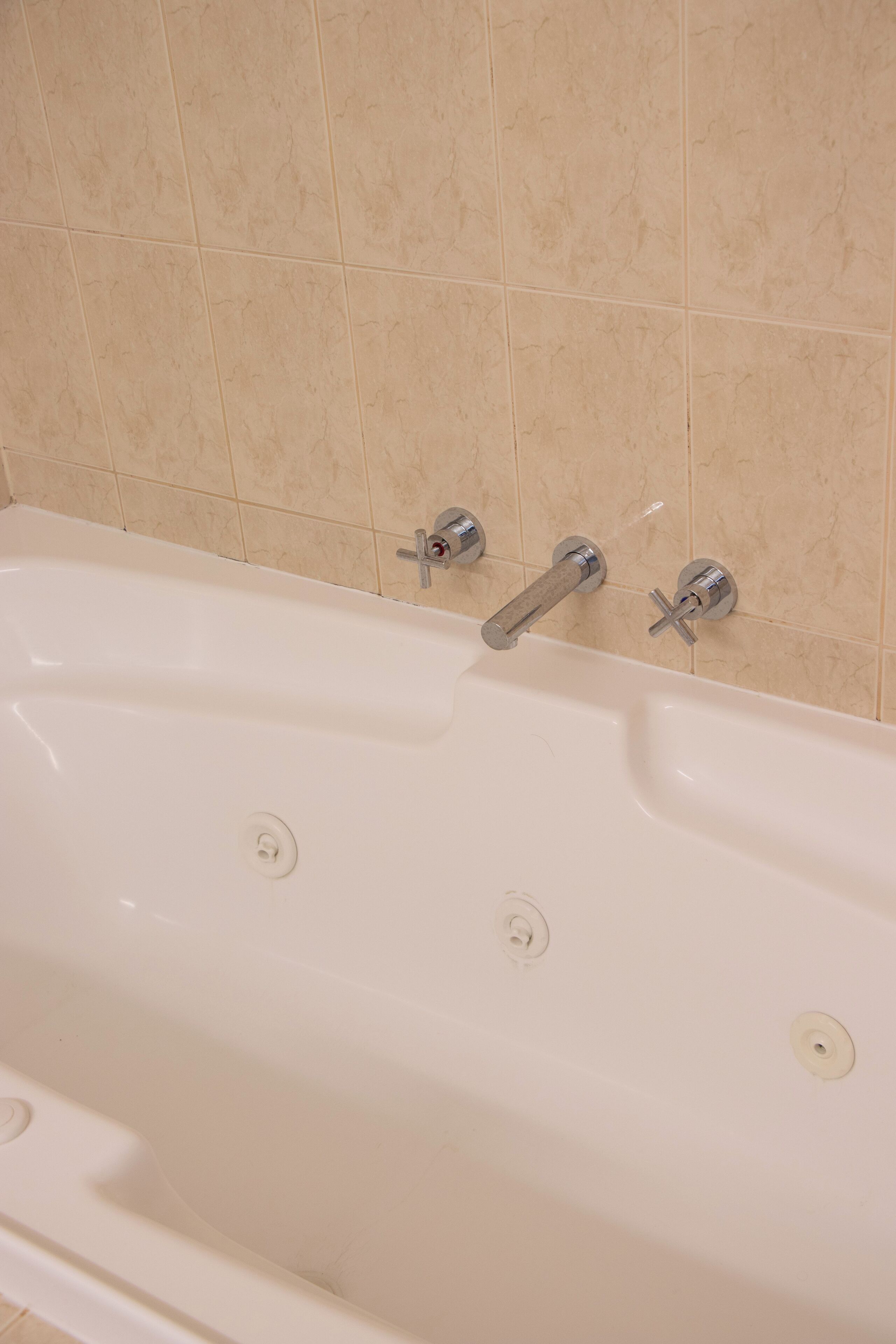 A bathtub with two faucets and a drain.