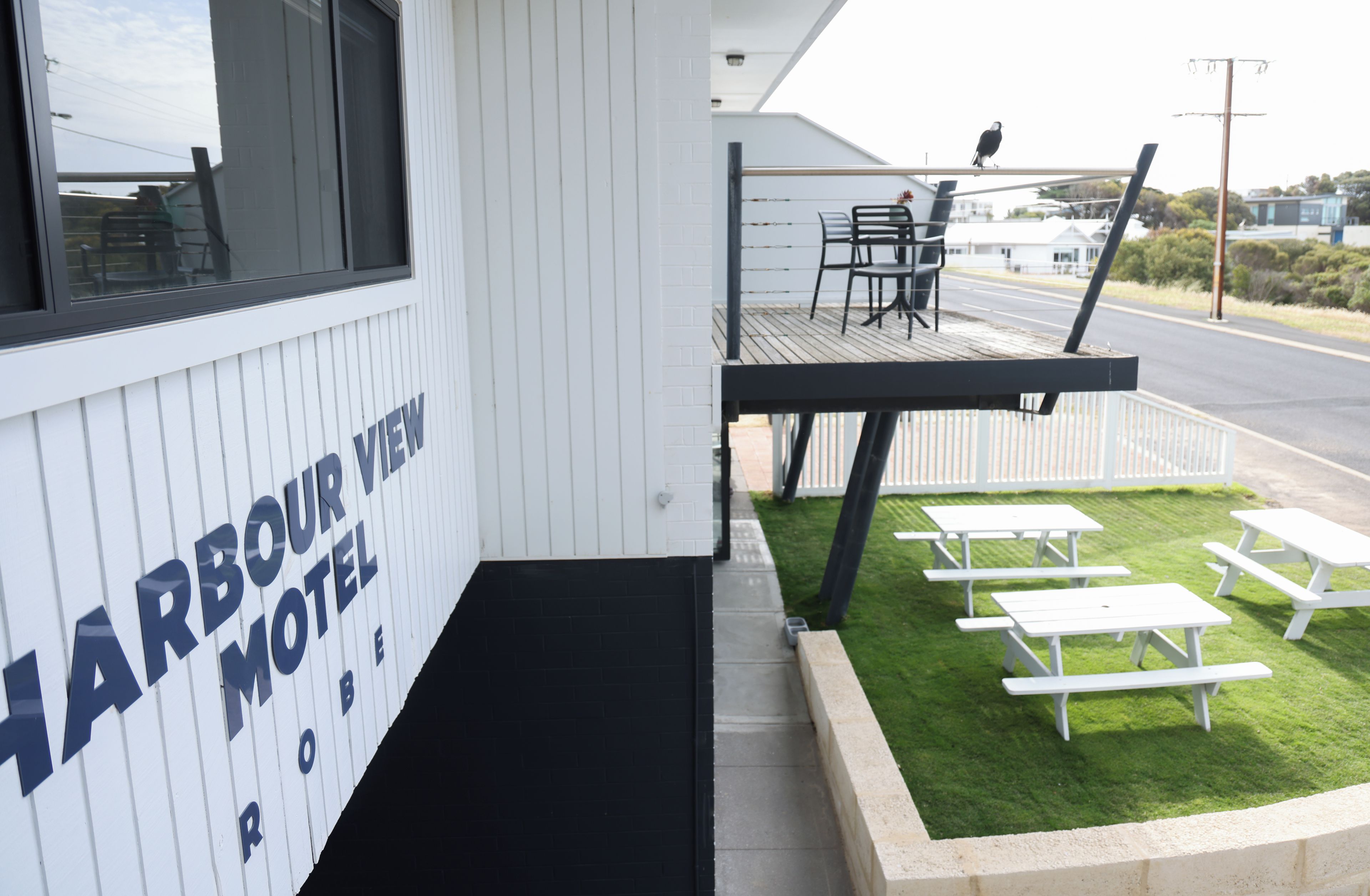 A Harbour View Motel with a deck area featuring outdoor seating and a view of the street.