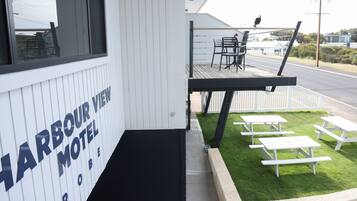 A Harbour View Motel with a deck area featuring outdoor seating and a view of the street.