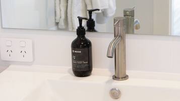 A bathroom with a white sink, a black soap dispenser, a silver faucet, and a towel rack with white towels.