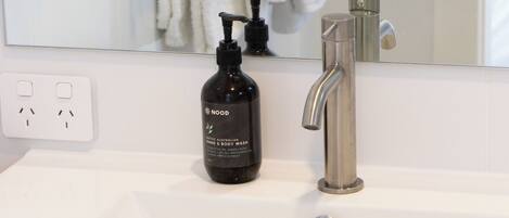 A bathroom with a white sink, a black soap dispenser, a silver faucet, and a towel rack with white towels.