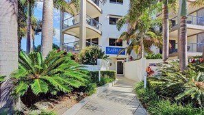 A modern multi-story hotel with a central courtyard, palm trees, and a reception area. - Raffles Mooloolaba (Mooloolaba)