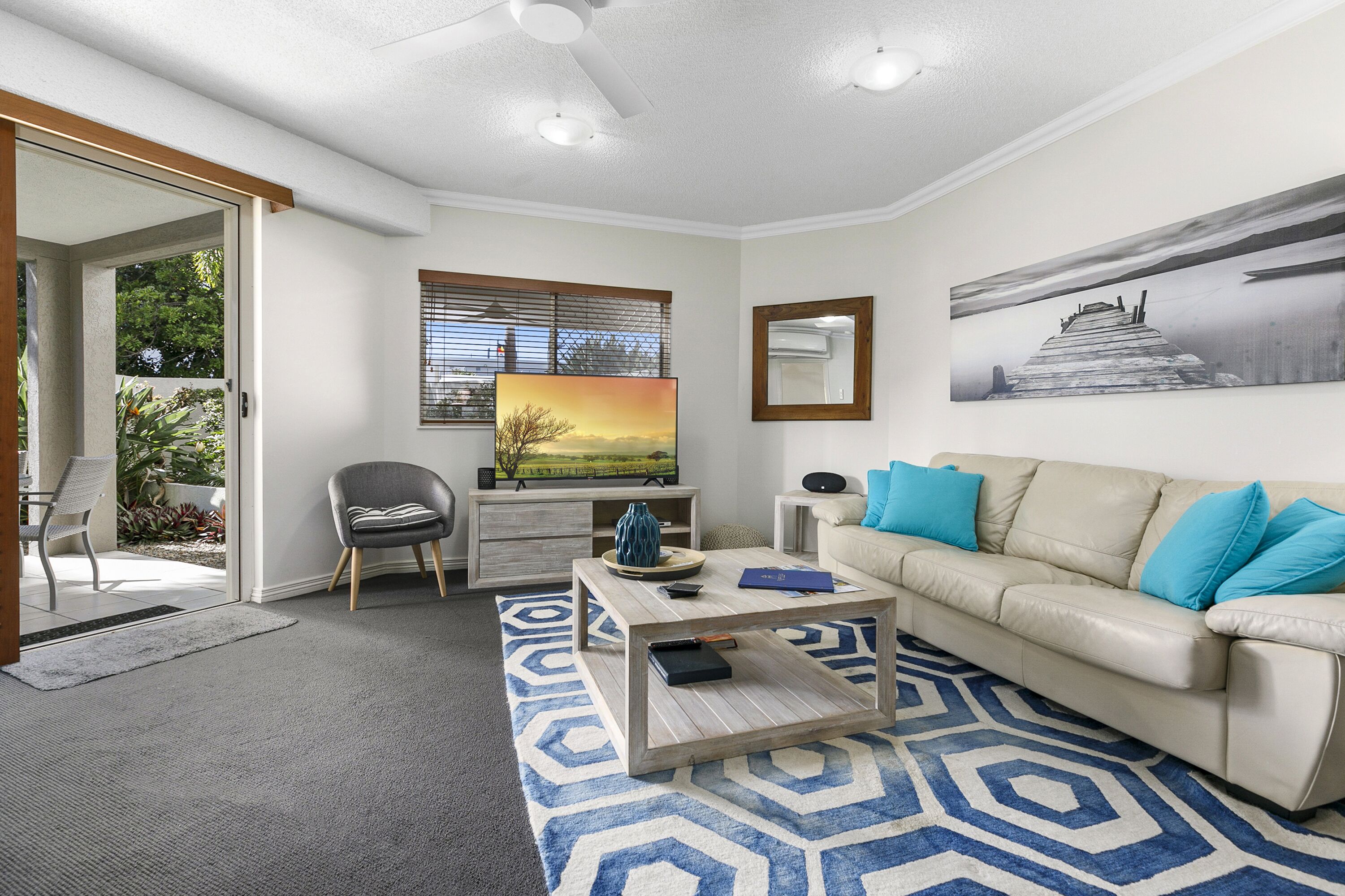 A modern living room with a sofa, coffee table, and a painting on the wall.