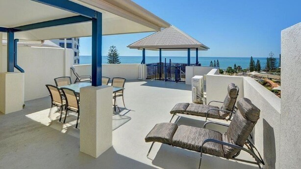 A covered outdoor area with a dining table and chairs, a gazebo, and a view of the sea. - Raffles Mooloolaba (Mooloolaba)