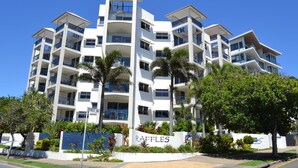 A multi-story hotel with balconies, a sign reading "RAFFLES," and palm trees in the foreground.