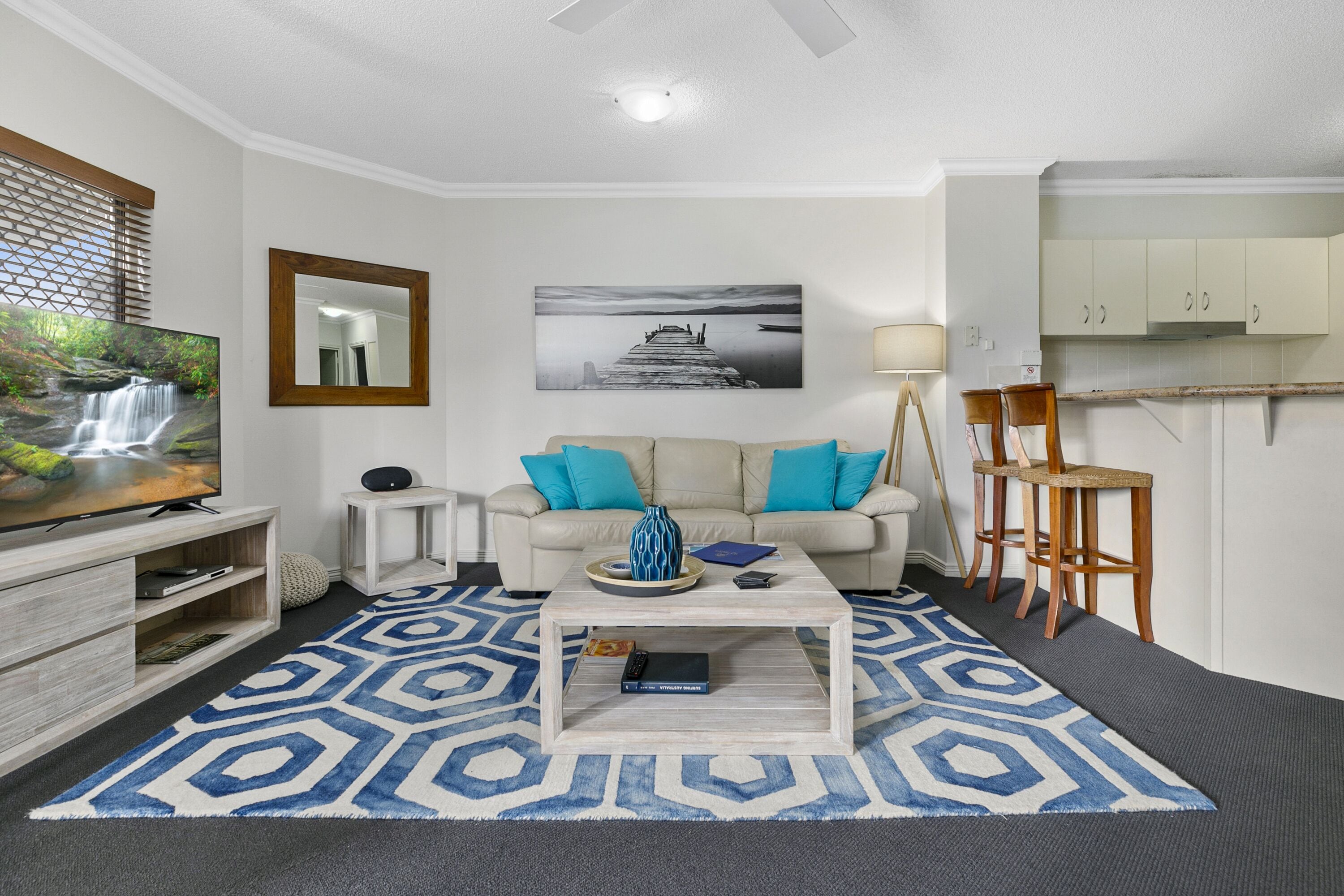 A living room with a sofa, coffee table, TV, and artwork.