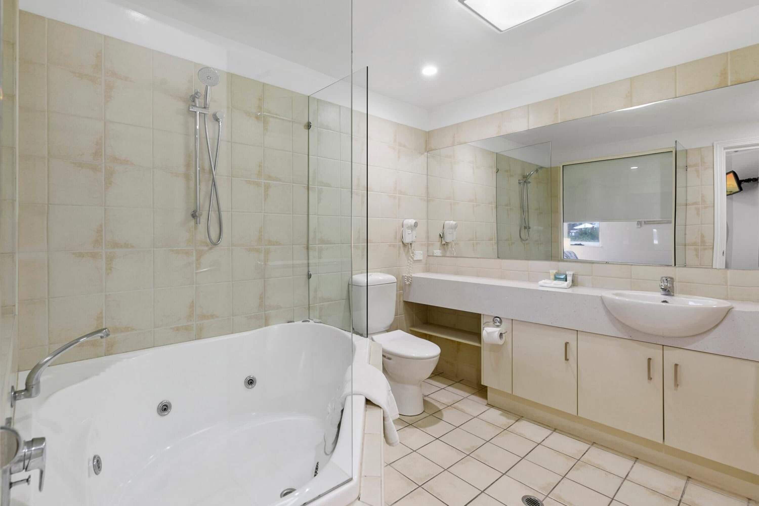 Une salle de bain moderne avec une baignoire sur pieds, des toilettes, une douche à parois de verre et un meuble-lavabo avec un évier et un miroir.