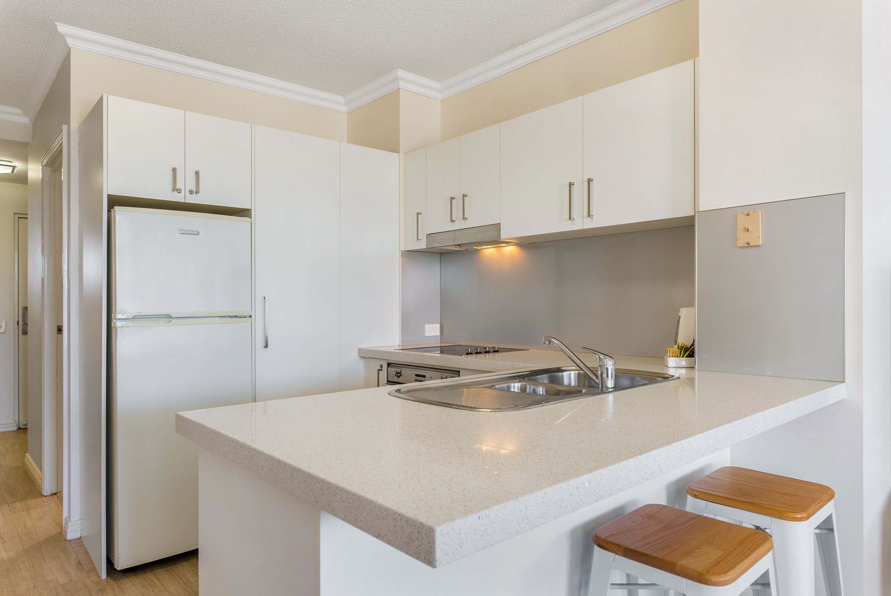 A modern kitchen with white cabinetry, a stainless steel sink, and a built-in oven.