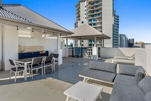 Una terraza en la azotea con asientos al aire libre, un bar y vistas de la ciudad.
