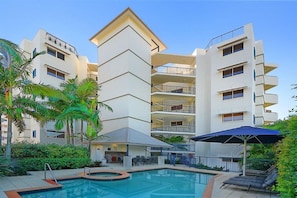 A modern hotel with a pool area, outdoor seating, and multiple balconies. - Raffles Mooloolaba (Mooloolaba)