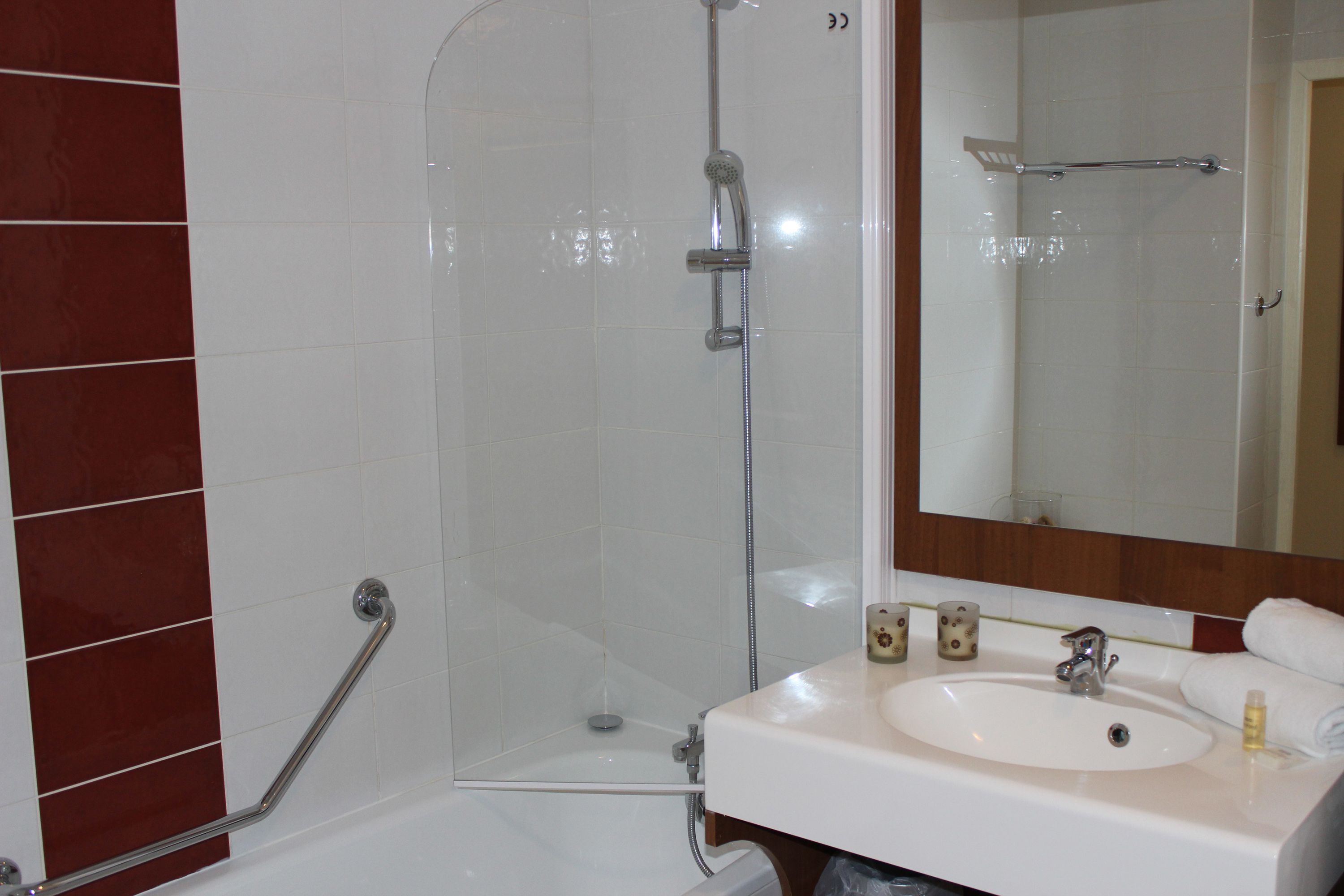 Un baño con ducha, lavamanos y espejo.