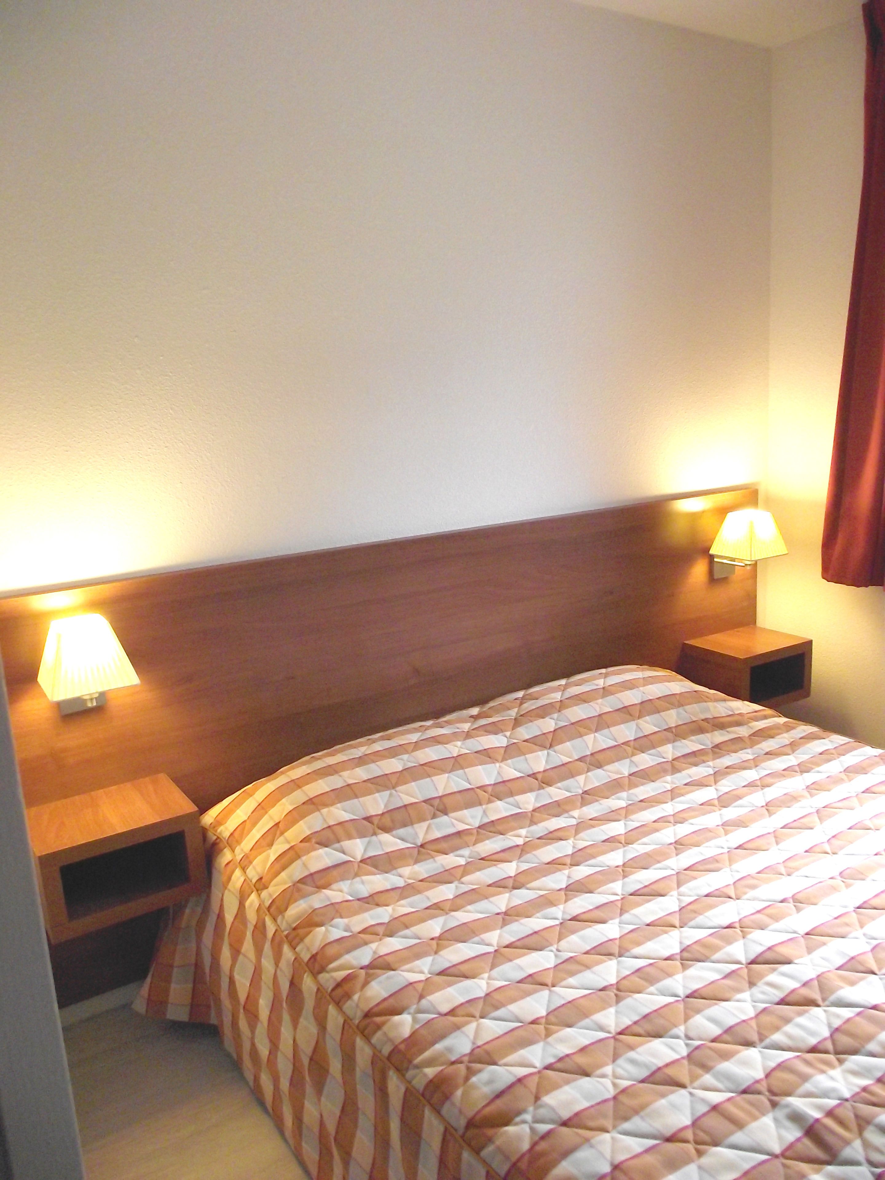 Ein Hotelzimmer mit einem Bett, zwei Nachttischen und zwei Wandleuchten.