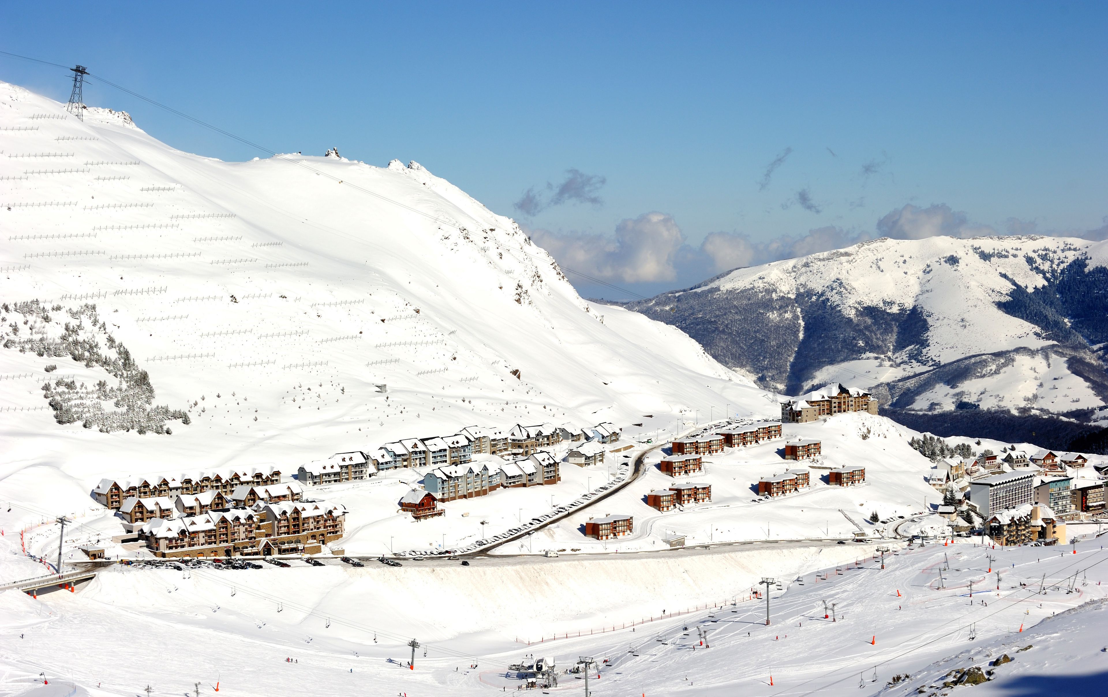 A snow-covered ski resort with multiple lodges, a ski lift, and a mountain backdrop.