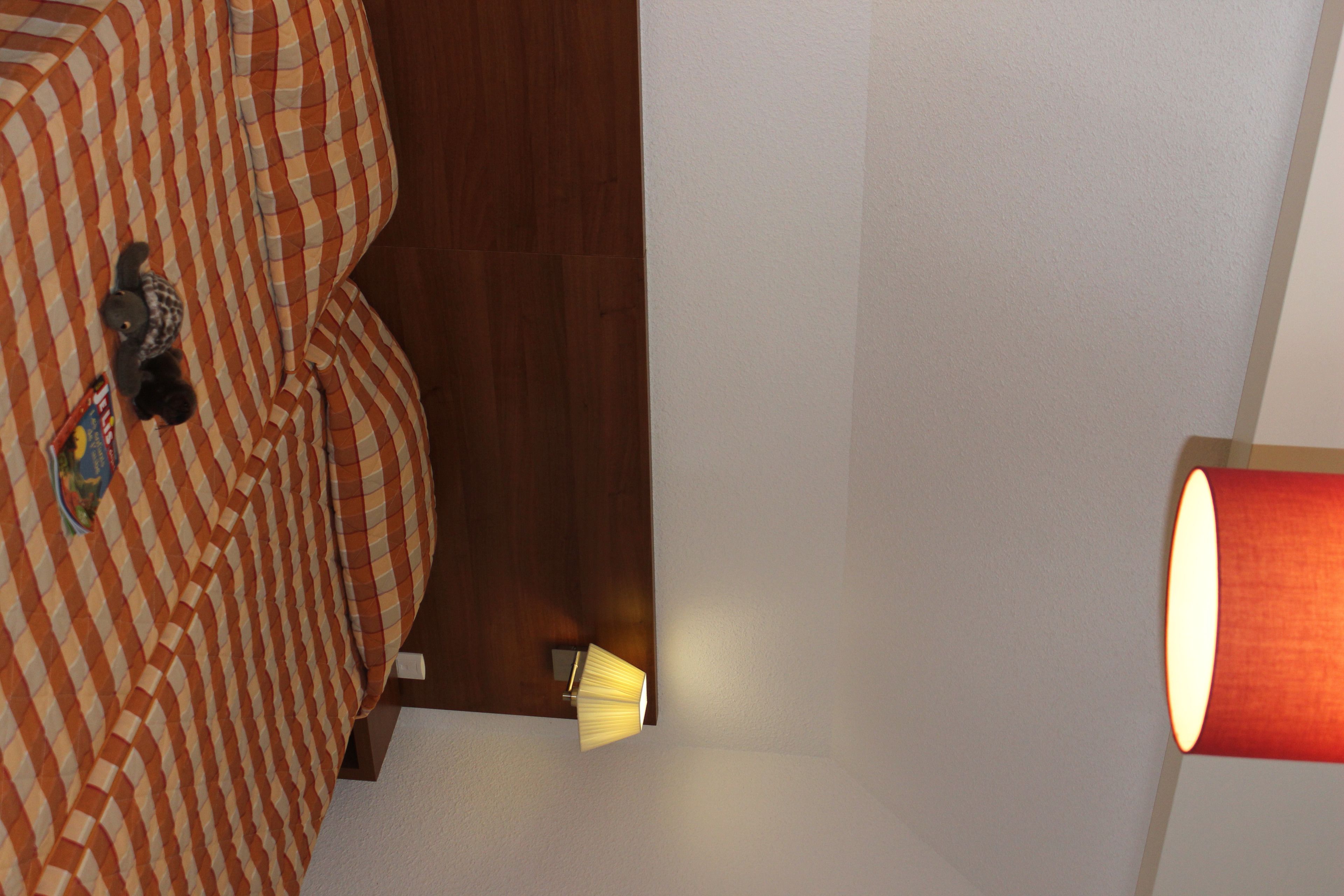 A room with a striped bed, a wooden door, and a red lamp.