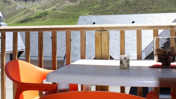 A wooden deck with a table and orange chairs, overlooking a mountainous landscape. - Résidence Tourmalet (Bagnères-de-Bigorre)