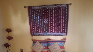 Una cama con una colcha estampada, almohadas y un cabecero decorativo.