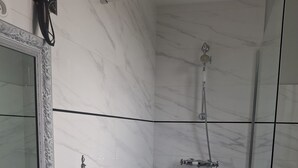 Un baño con lavamanos, espejo, toallero, ducha y baldosas de suelo con diseño.
