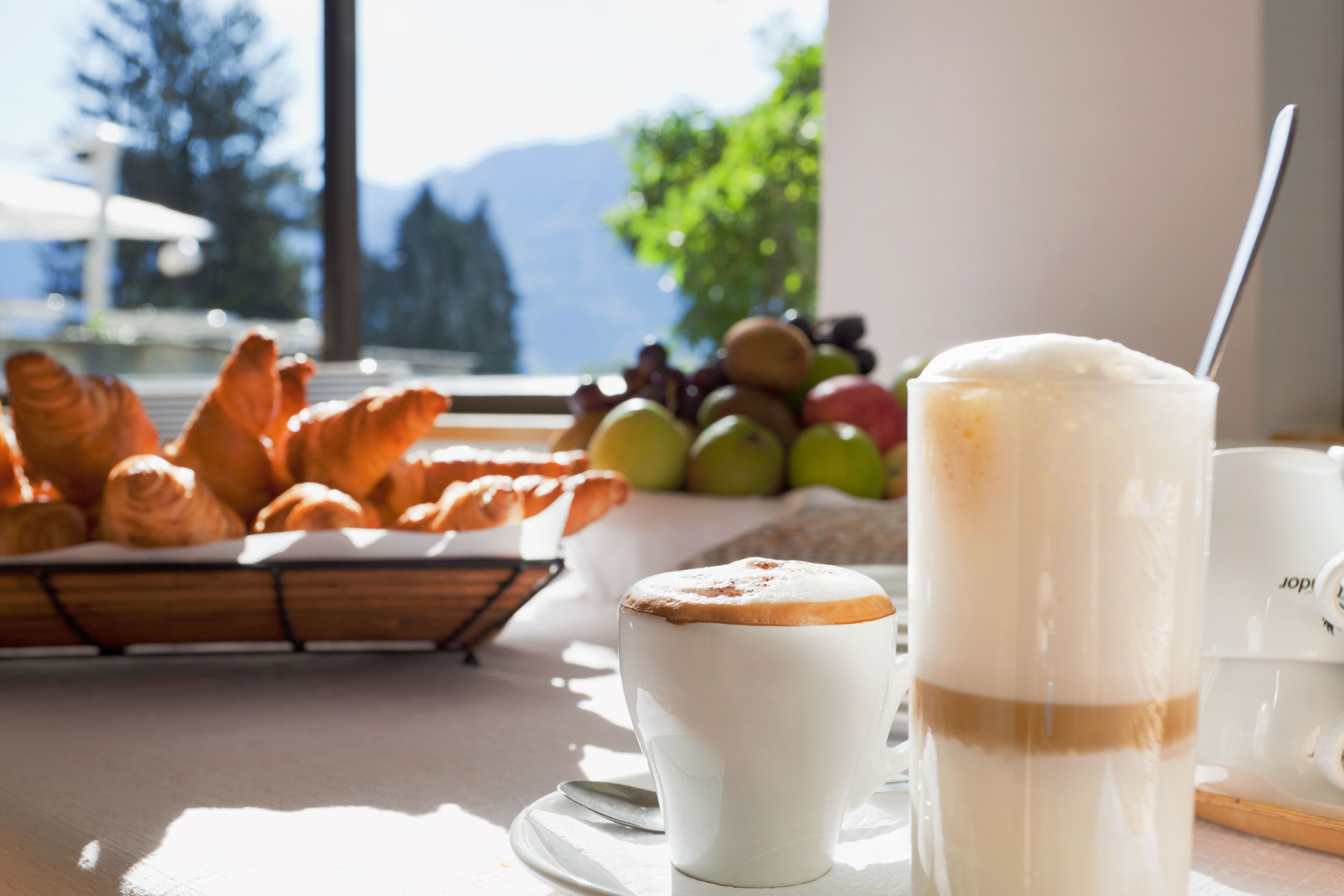 A breakfast setting with croissants, a cup of coffee, and a glass of milk.