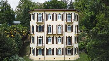 Un immeuble à étages doté d’une façade symétrique, de nombreux balcons et d’une pelouse bien entretenue.
