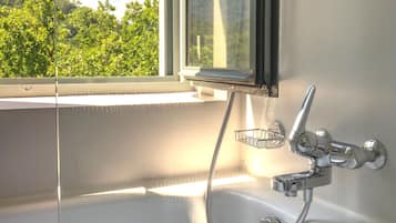 A bathroom with a bathtub, a shower, and a window.