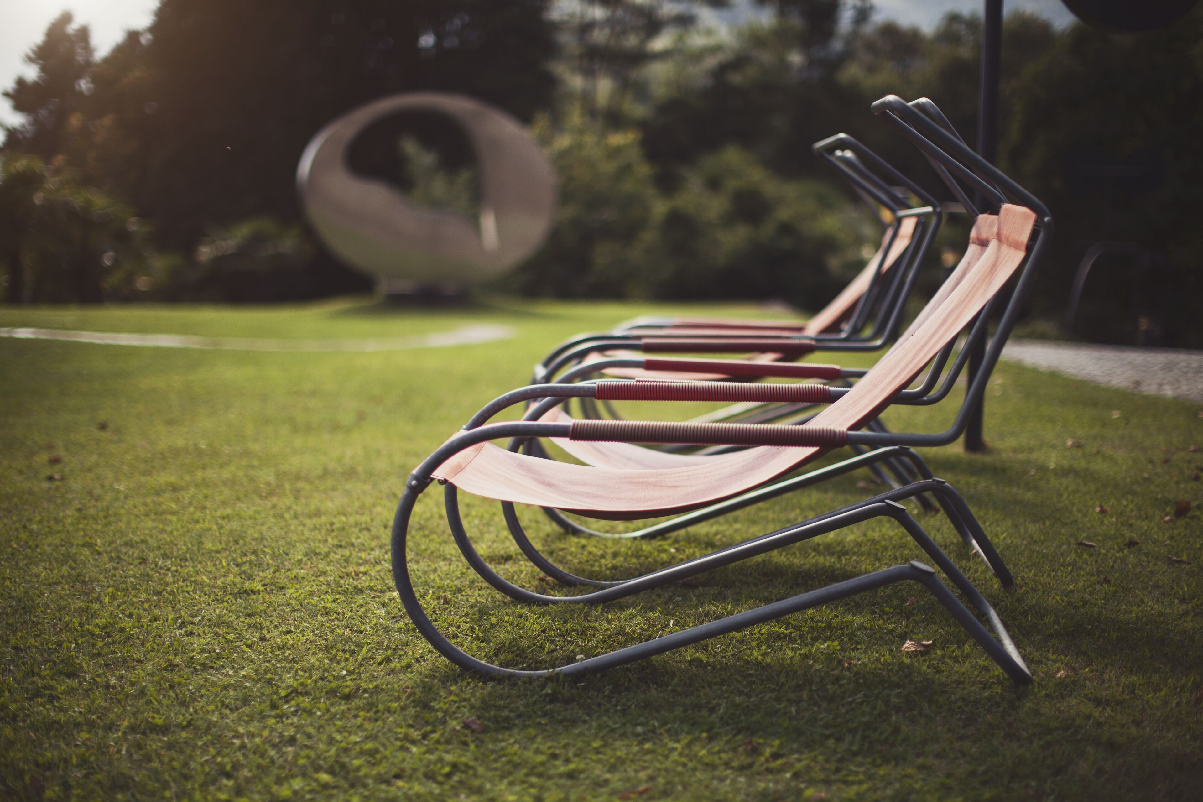 Een rij metalen stoelen met houten latten op een gazon.