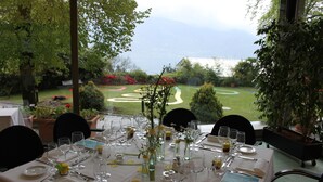 A table set for a meal with a view of a landscaped garden and distant mountains. - Monte Verità (Ascona)