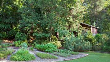 A garden with a wooden structure, surrounded by dense greenery and a gravel path.