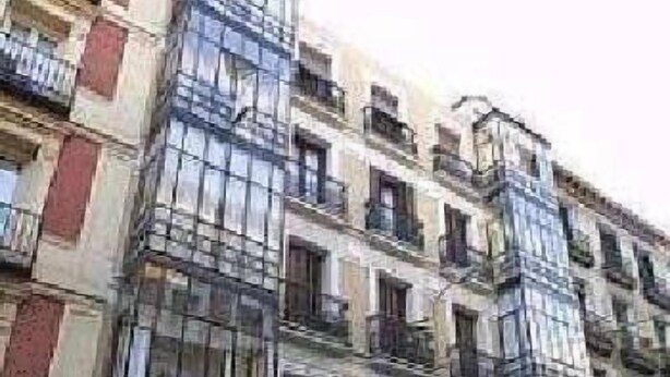 A multi-story building with a mix of residential and commercial spaces, featuring balconies and storefronts. - Hostal Abril (Madrid)