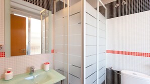 A bathroom with a glass shower enclosure, a sink with a green countertop, a white toilet, and a mirror above the sink. - Hostal Abril (Madrid)