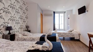 A hotel room with two beds, a desk, a chair, a TV, and a window with curtains. - Hostal Abril (Madrid)
