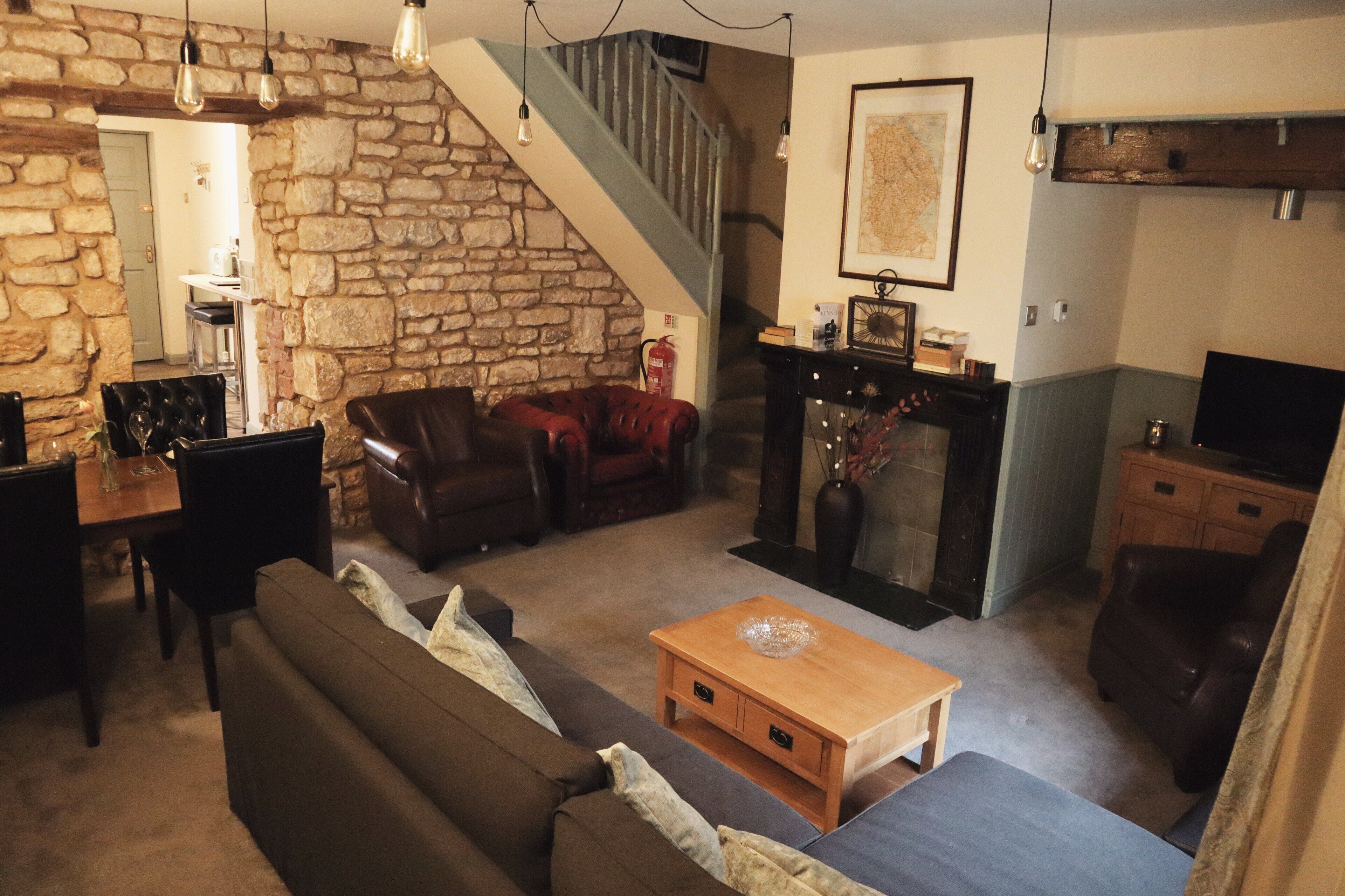 A living room with a stone wall, a staircase, a wooden coffee table, and a television.