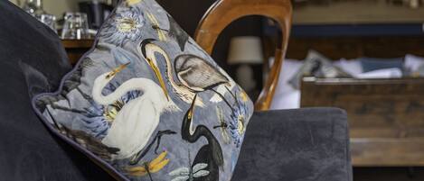 Un canapé de couleur sombre agrémenté d’un coussin décoratif orné de motifs d’oiseaux et de fleurs.