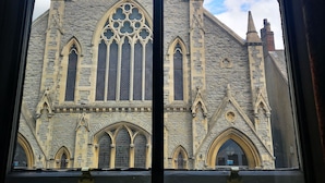 A view of a stone building with pointed arches and a large rose window through a window. - Duke William Hotel (Lincoln)