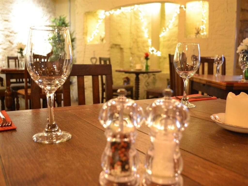 A dining table with wine glasses and salt and pepper shakers.