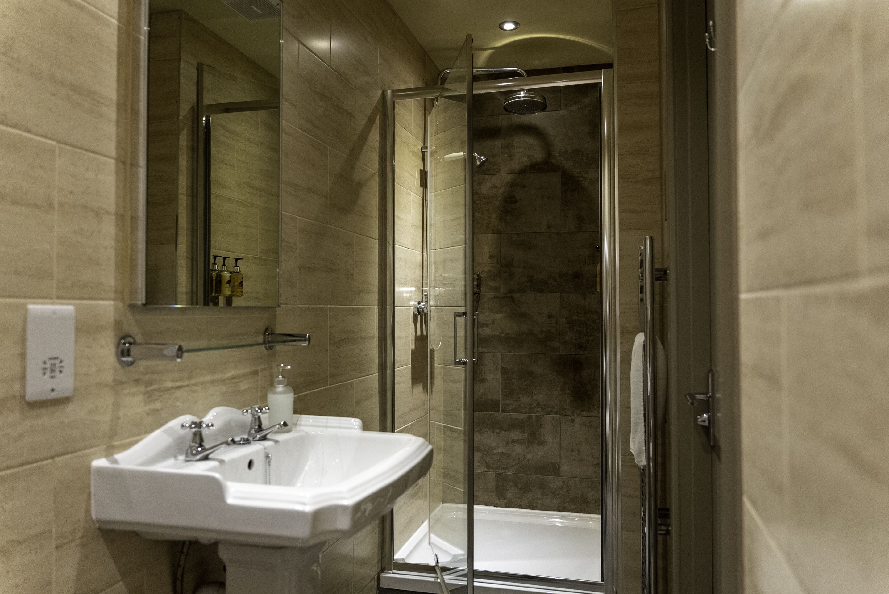 A modern bathroom with a glass-enclosed shower, a white sink, and a mirror.