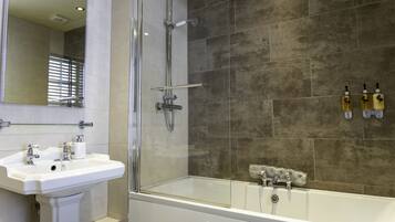 Un baño moderno con ducha de vidrio, lavamanos blanco y bañera.