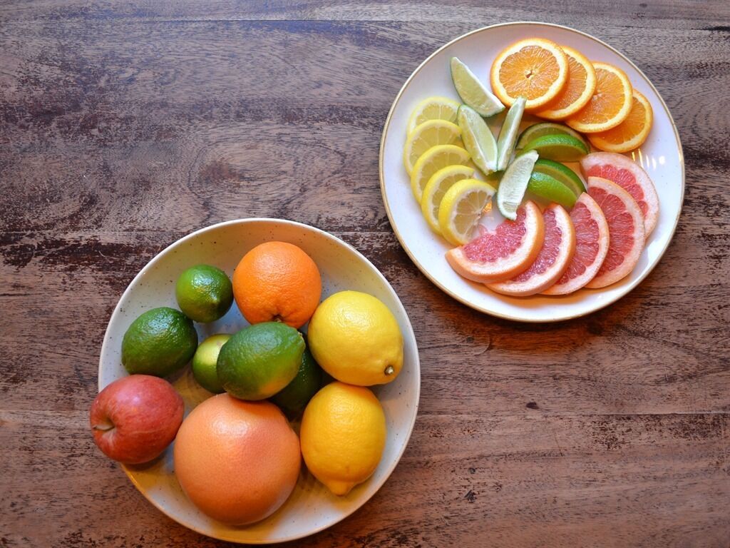 Two bowls of fruit on a wooden table.