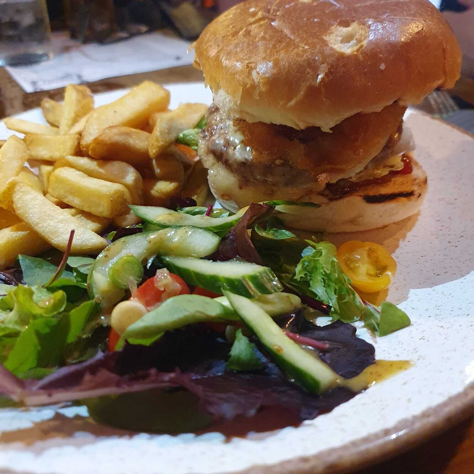Une assiette avec un hamburger, des frites et une salade.