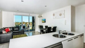 Una cocina moderna con una isla grande, comedor y sala de estar con sofá y balcón.