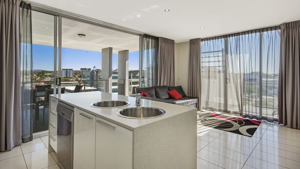 Una cocina moderna con una isla central, dos fregaderos y una zona de comedor con vistas a la ciudad.