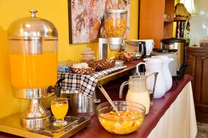 A breakfast buffet setup with a juice dispenser, cereal, and various food items. - Kelta Hotel (El Calafate)