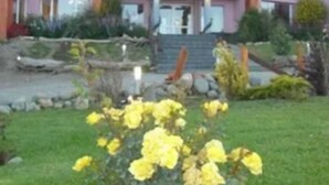 Un edificio de varios pisos con una entrada destacada, un jardín bien cuidado con flores amarillas y un camino de piedra que lleva a la entrada.