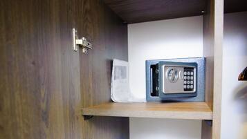 A wooden cabinet with a microwave on the top shelf and a towel on the bottom shelf.