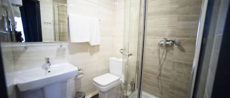 Un baño moderno con ducha envuelta en vidrio, un lavabo blanco y un inodoro.