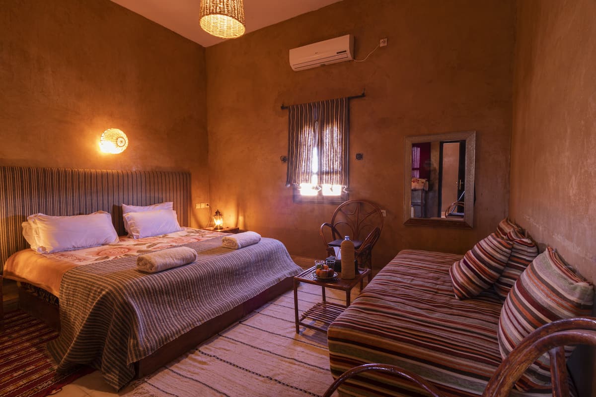 Une chambre confortable avec un lit, un canapé, un fauteuil et une petite table.
