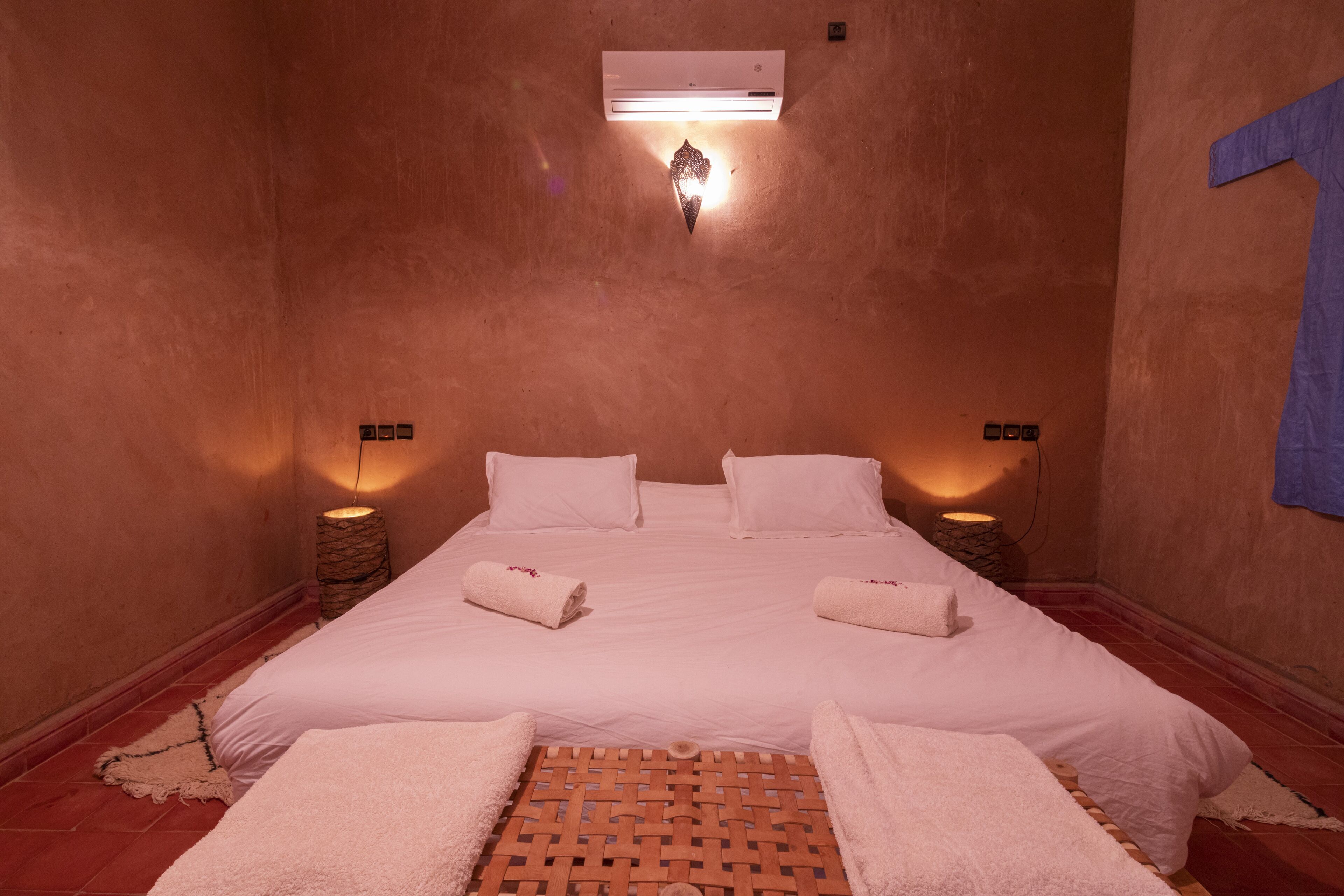 Una habitación con cama, dos mesitas de noche y un aire acondicionado.
