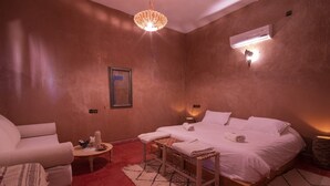 Ein Schlafzimmer mit Bett, Nachttischen, einem Sessel und einer Pendelleuchte.