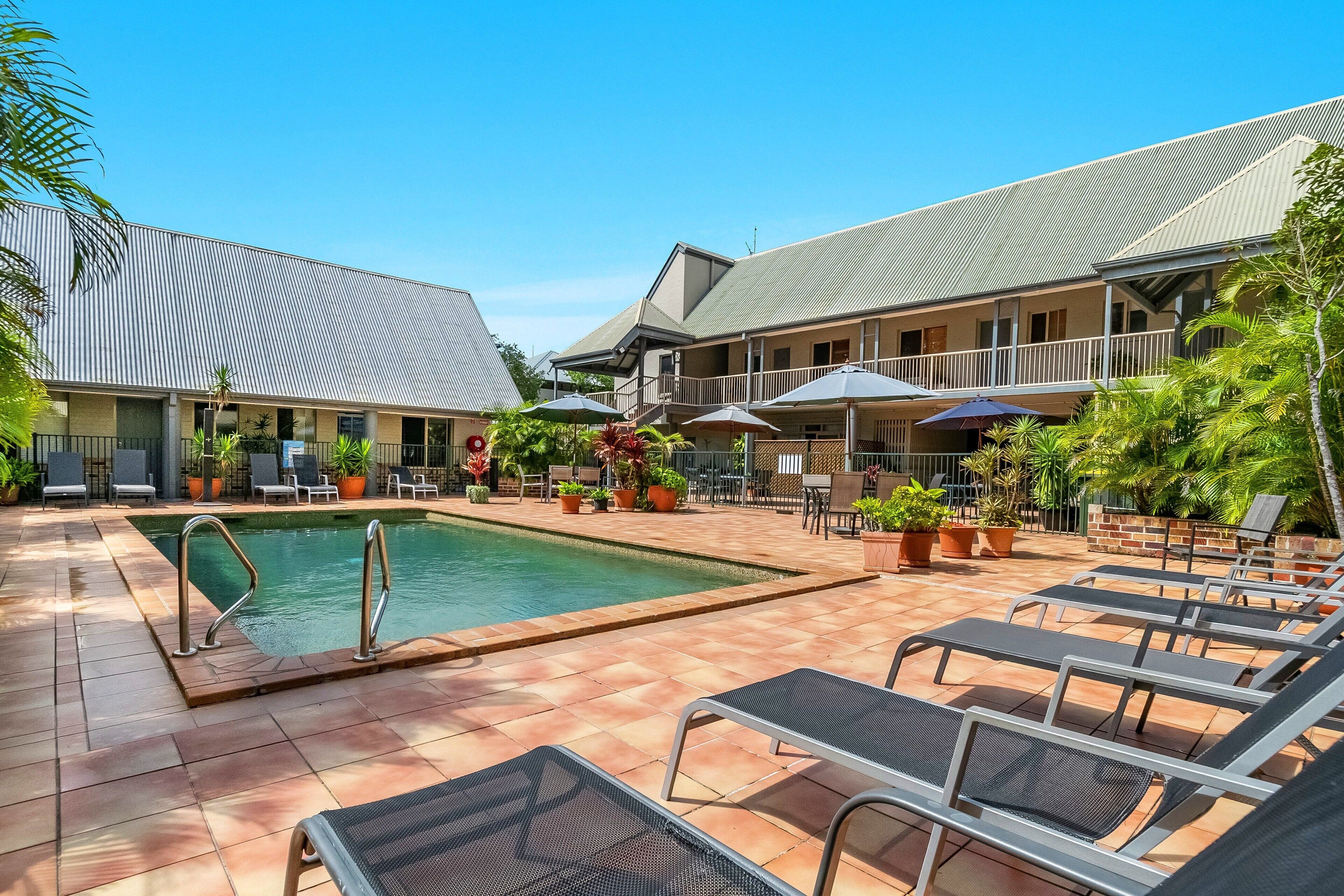 A hotel courtyard with a swimming pool, lounge chairs, and outdoor seating areas.